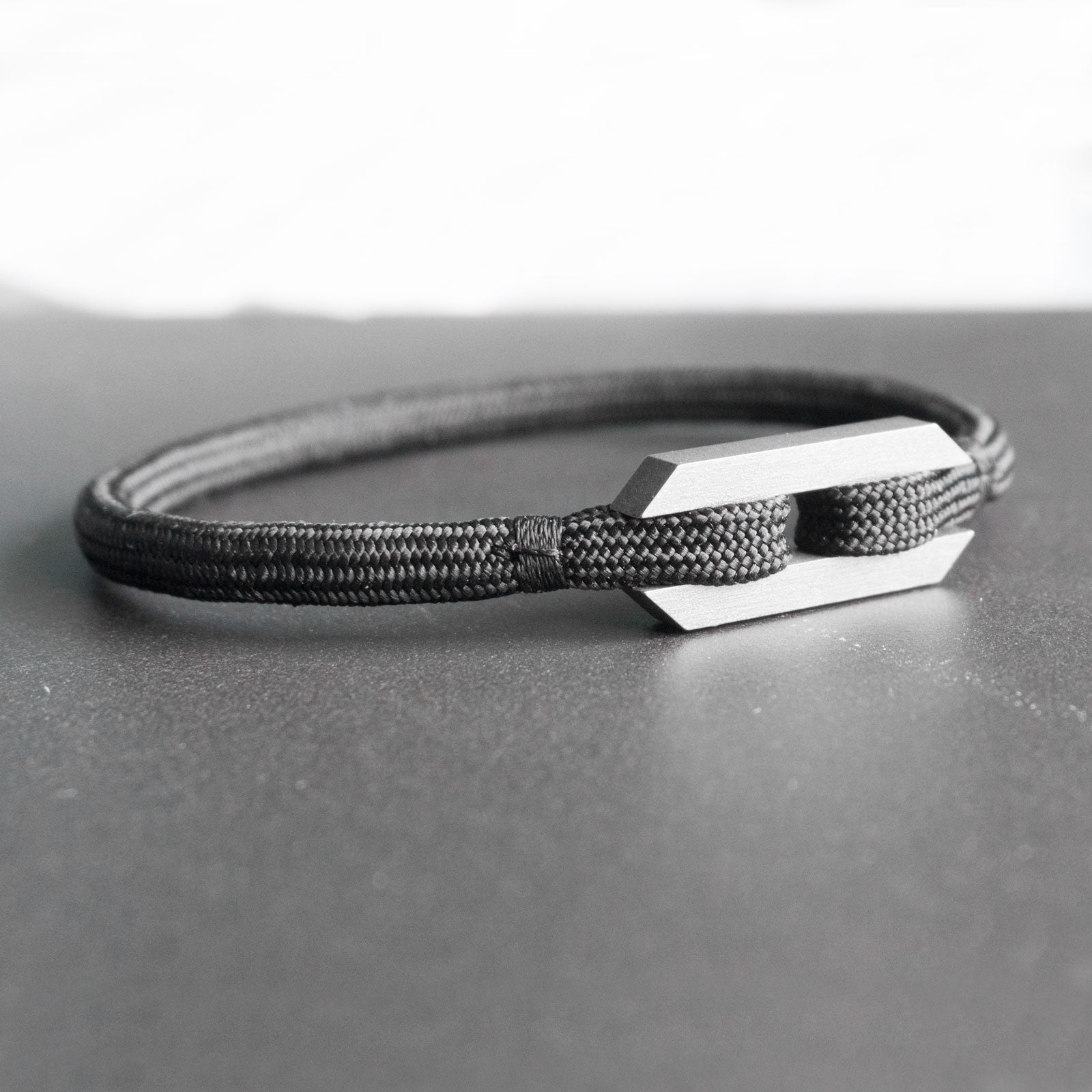 The Stoa bracelet in titanium stands for simplicity, purity and a seamless appearance. Taking its name from the eponymous greek walkways, the rope feels as it was surrounded and protected by 2 imposing pillars, with no visible opening mechanism. The bracelet is handmade from grade 5 titanium and a nearly indestructible rope.