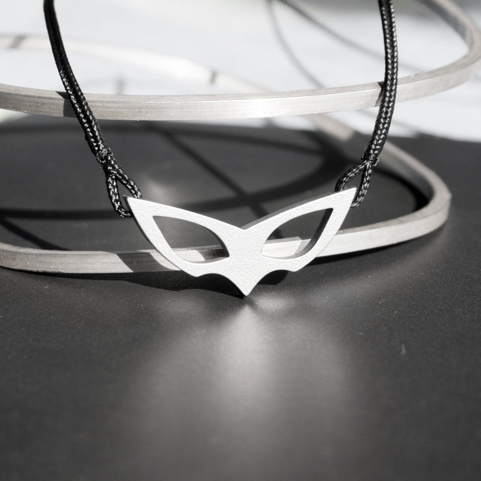 Joker's mask as a pendant, perfectly recreated with faithful proportions. A seemingly simple 2D rendition of the mask and a minimalist, timeless piece to wear. Entirely handcrafted from grade 5 titanium.