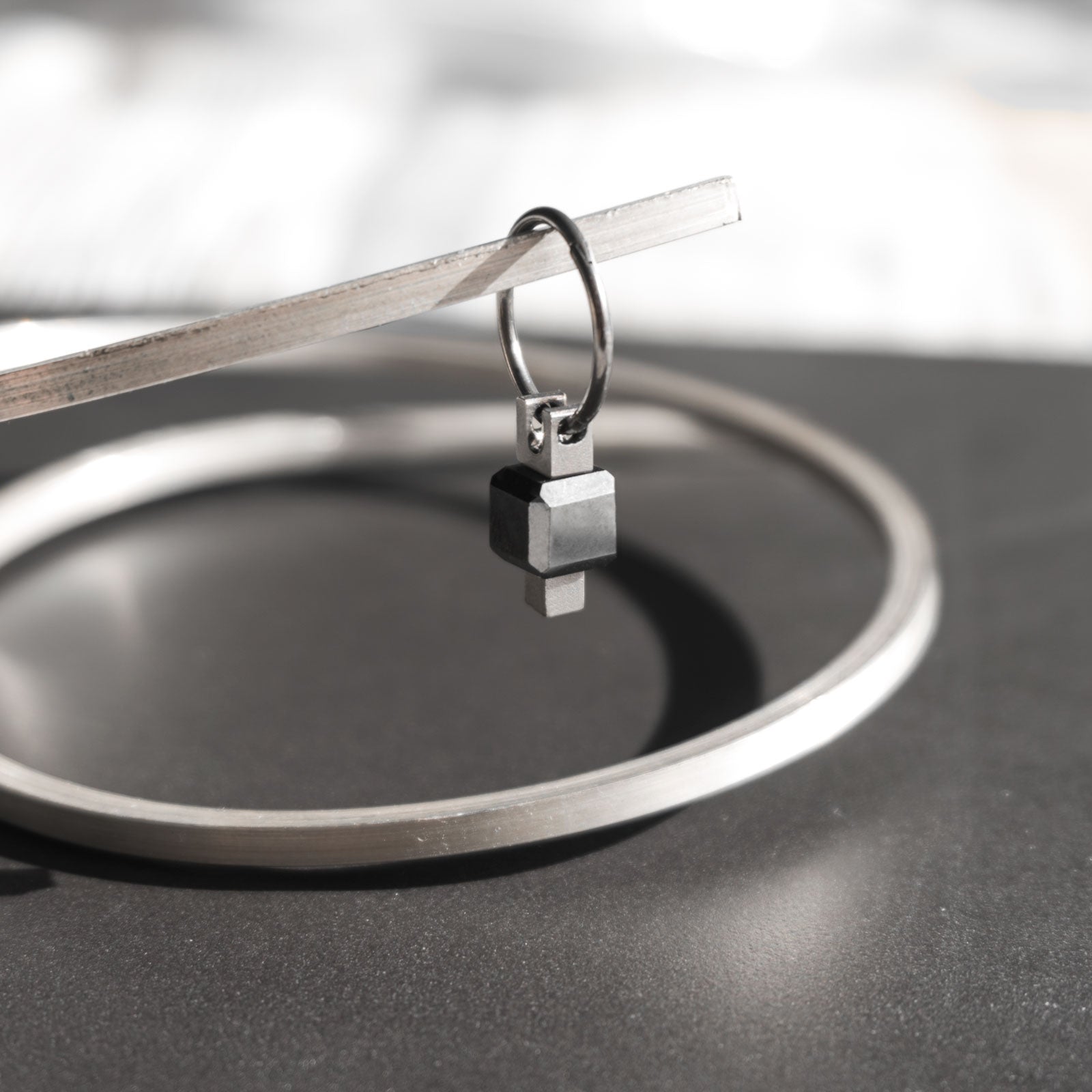 The Black Box earring takes inspiration from Nier Automata, as an echo to the black box from the game itself, with a unique cubic black diamond set in. It is handcrafted from grade 5 titanium.