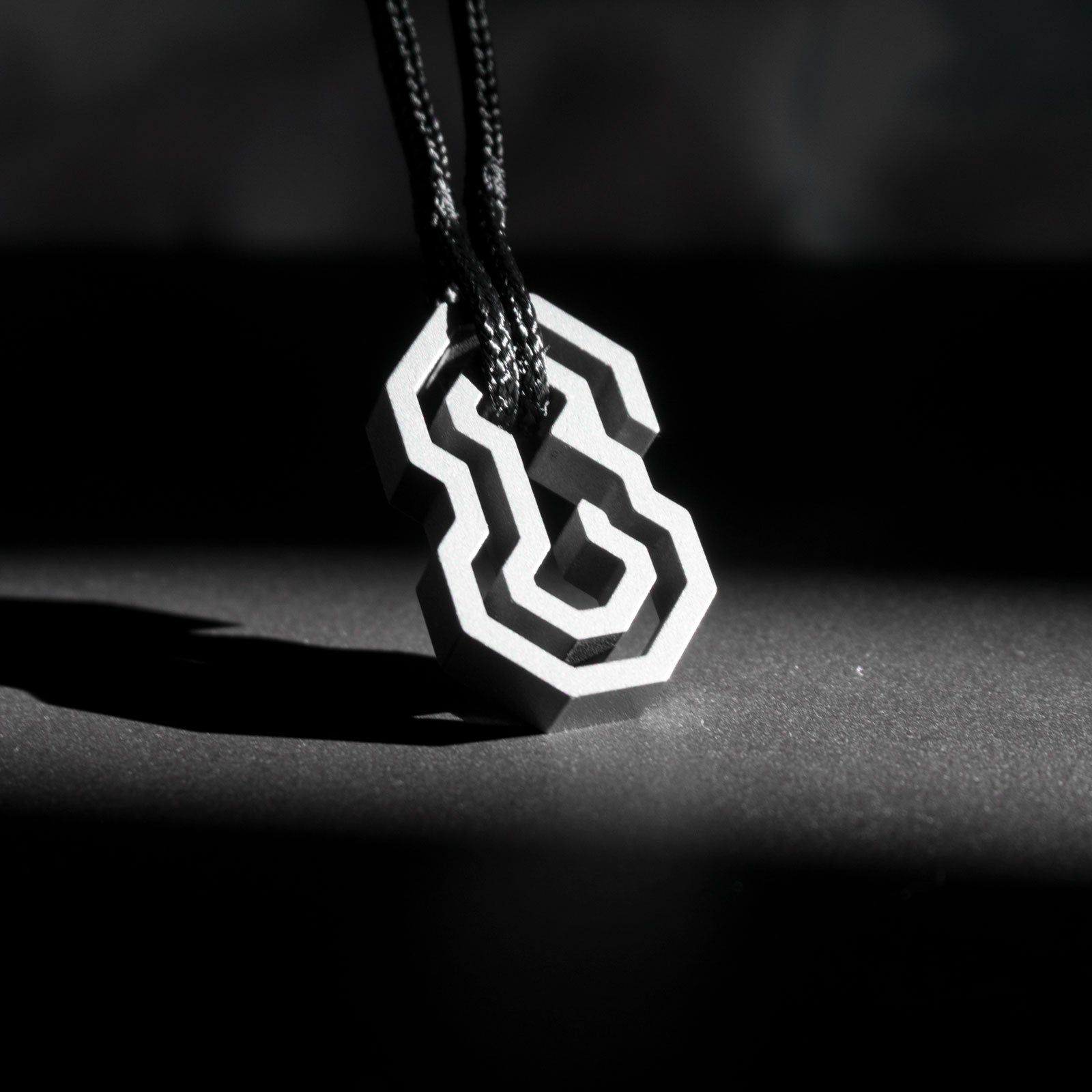The Daidalos is a minimalist, timeless pendant, handmade from grade 5 titanium and a nearly indestructible rope. Its shape is inspired by the eponymous maze, wherein you need to slide the rope through the maze, until it reaches the center and securely nests itself, almost like a mini puzzle.