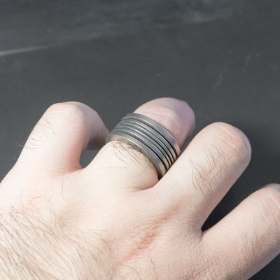 This is the Bastion Alter ring, a minimalist and imposing ring with fin-like slits that are proportional to each other following the golden ratio. This ring plays with the contrasting shadows to give it a unique look when on the finger. Being crafted from titanium it is very light, comfortable to wear and it is fully biocompatible.
