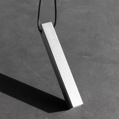The Stoa pendant in titanium stands for simplicity, purity and a seamless appearance. With its imposing monolithic structure, it takes its name from the eponymous greek walkways, impervious to time, stoic.