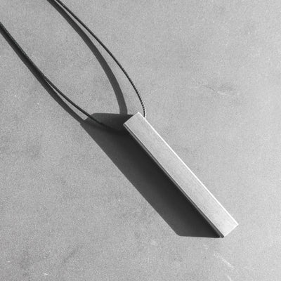 The Stoa pendant in titanium stands for simplicity, purity and a seamless appearance. With its imposing monolithic structure, it takes its name from the eponymous greek walkways, impervious to time, stoic.