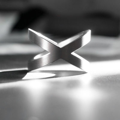 This is the Xenos ring. Shaped after a cross, the massive ring is yet refined, with simple, sharp lines. Despite its big and bold presence, the Xenos ring in titanium is very light and biocompatible.